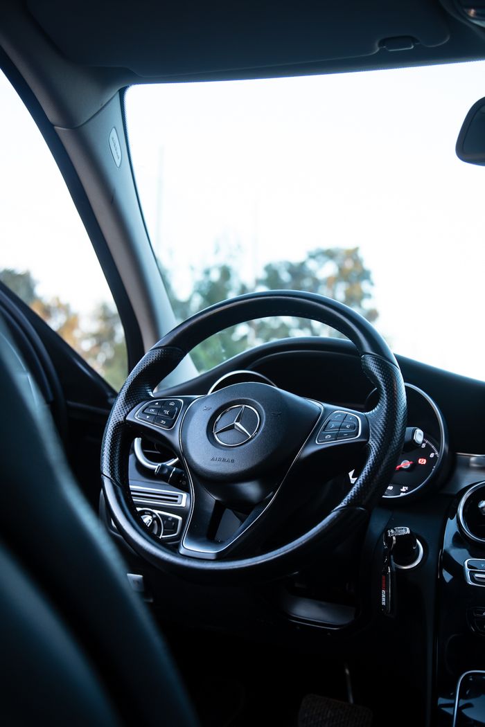 about-04 Close-up of a Mercedes-Benz car interior showcasing the steering wheel and dashboard.