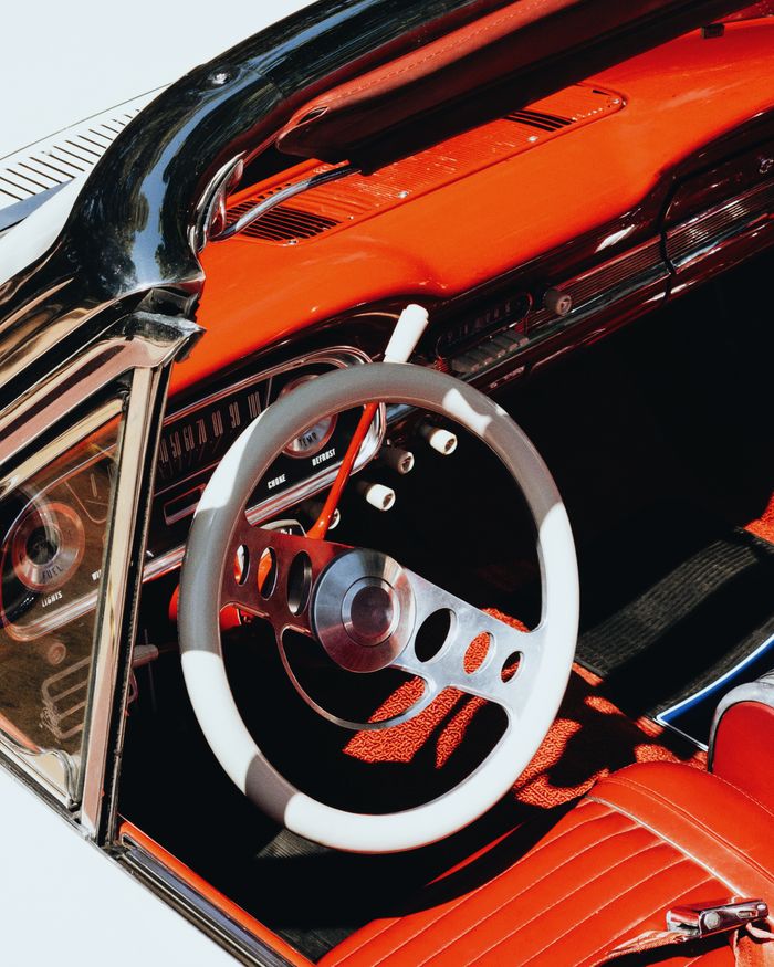 services-01 Close-up of a vintage convertible’s red dashboard and steering wheel, showcasing classic car design.