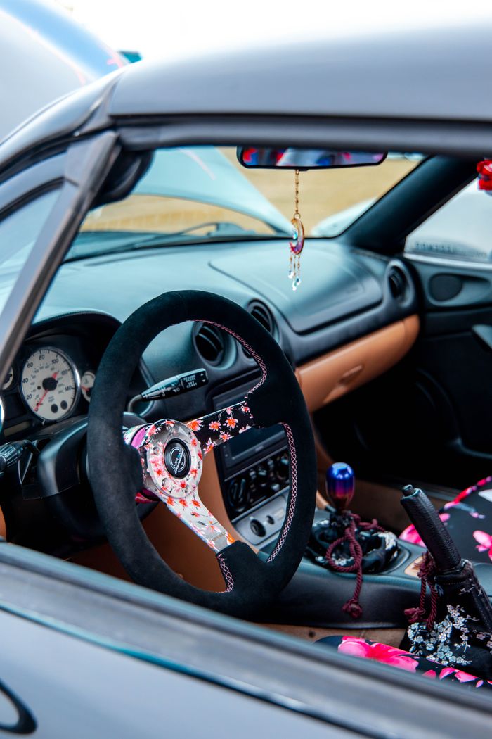 about-03 Bright car interior showcasing a custom floral steering wheel and vibrant accents.